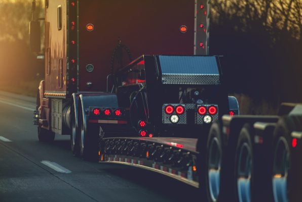 Semi Truck with Heavy Duty Platform Trailer on a Route. Transportation Industry.